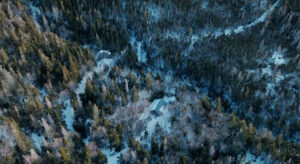 An aerial shot of the cabin, zoomed out to show the mountainside.