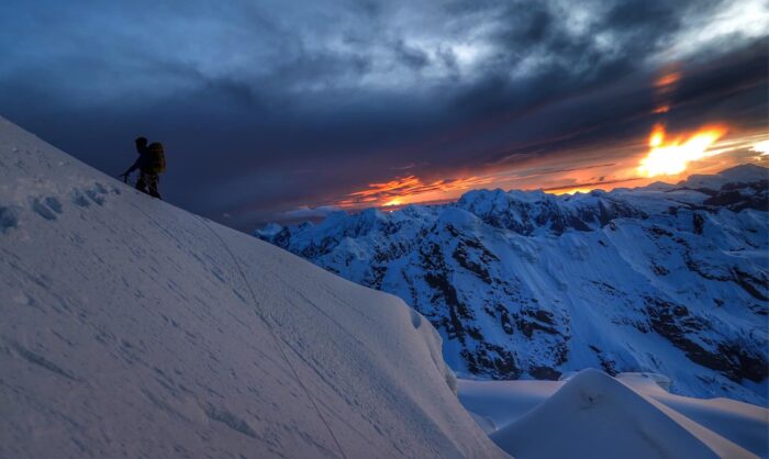 The climber alone on a snow slope at sunset. 