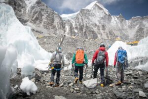 four sherpa climbers as seen from behind, as they head toward the mountains while walking on morraine terrain at Everest Base Camp