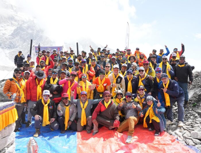 A large froup of people poses for a photo by a chorten in Everest Base Camp