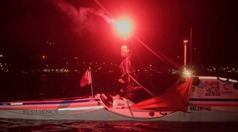 kayaker holds a red celebratory flare signaling the finish