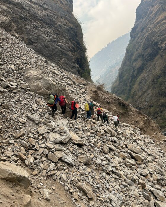 A small expedition team of Nepali climbers cross a steep scree slope.