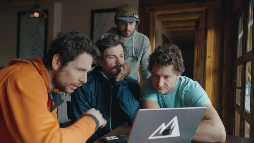 Four men crowded around a laptop.