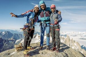 three climbers on a rocky, narrow top.