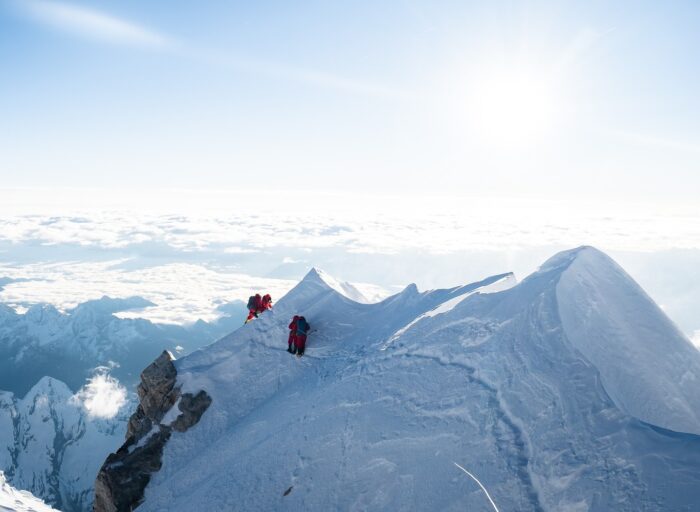 Climbers follow a rope on a side of a snowy summit ridge, near the summit of Makalu.