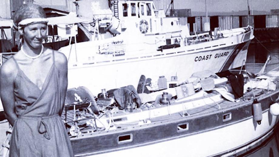 Black and white photo of a young woman in front of a coast guard boat.