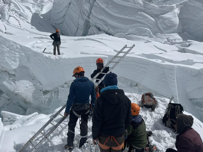 Sherpas on both sides of a crevasse holding aluminium ladders