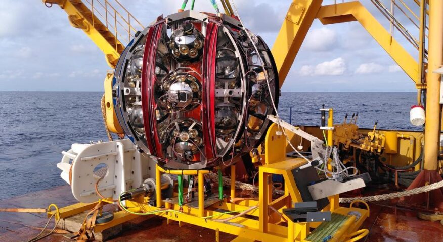 A large metal sphere suspended by a crane.