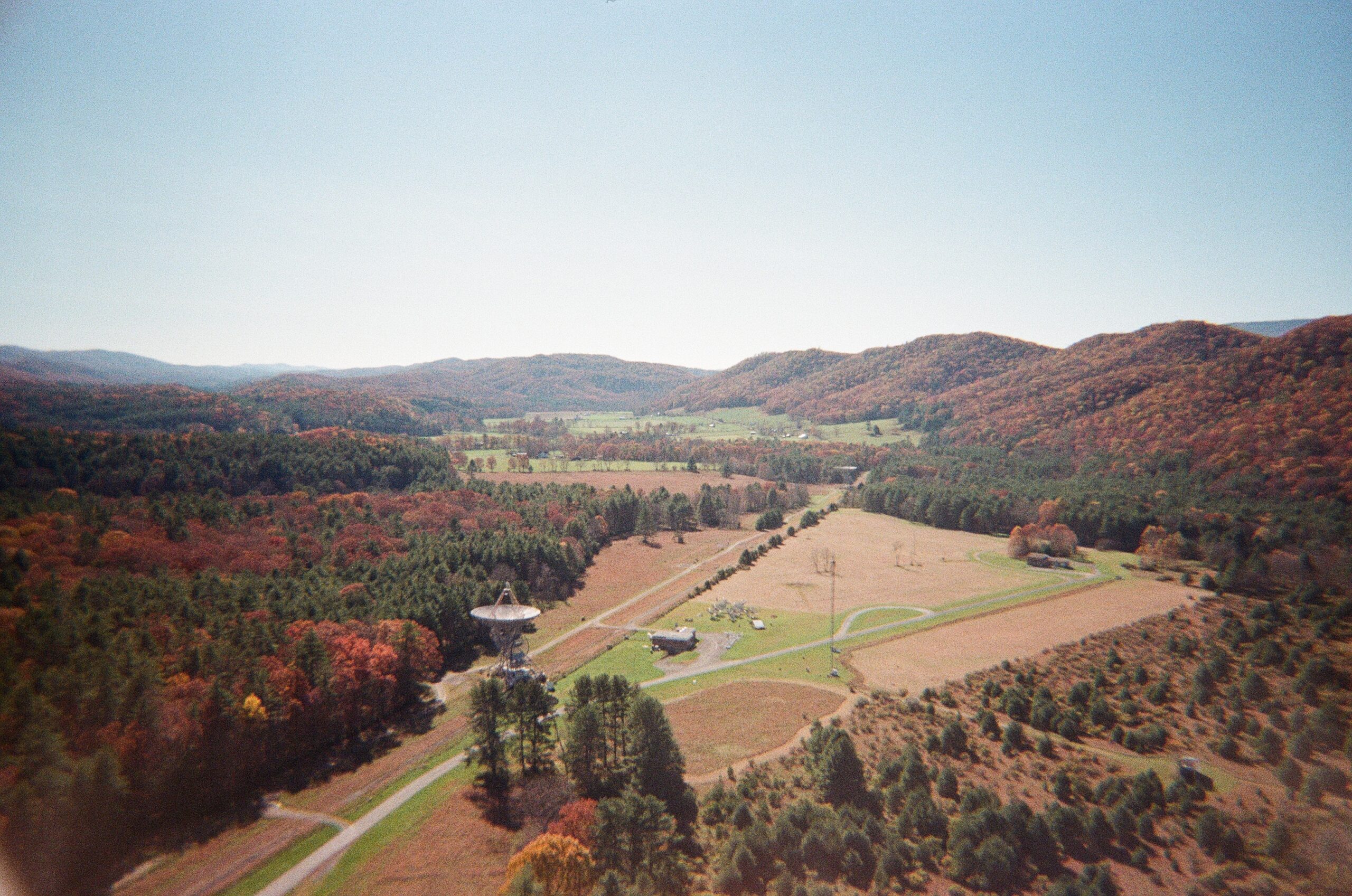 An aerial view of a forest in fall, with a telescope visible.