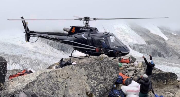 A helicopter avoids some rocks as it takes off from Kangchenjunga base camp.