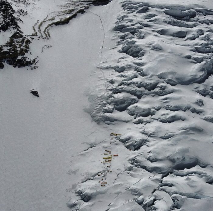 Aerial shot of the Lhotse fae with the tents of Camp 3 and a black line of climbers marching toward thge summit of Everest.