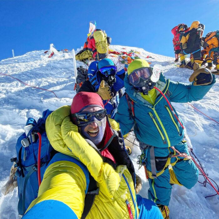 Climber takes a selfie on the summit of Everest with other climbers in the picture.