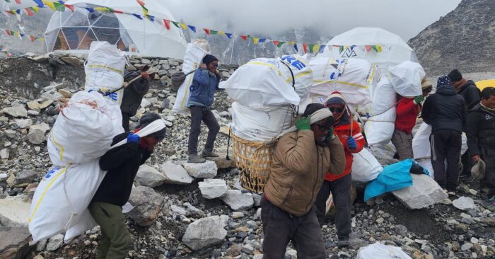 Nepalese carrying huge sacks of garbage on glacial terrain at Everest Base Camp.