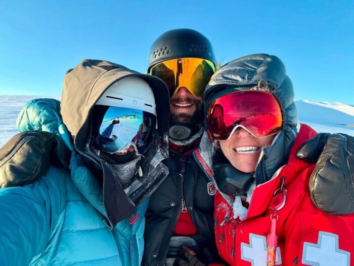 three skiers in goggles in white Arctic