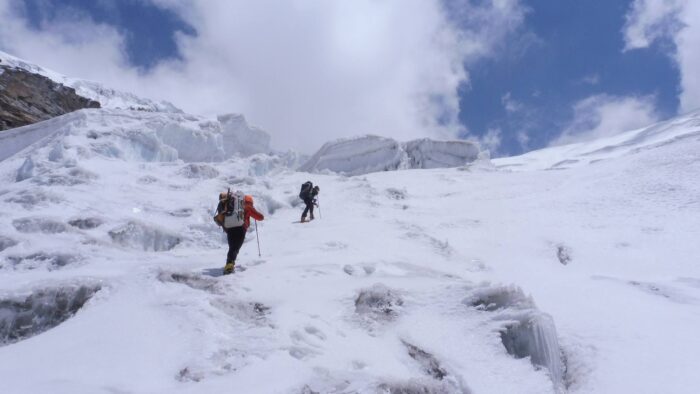 Climbers on a glacier with seracs above them.