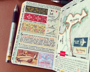 An open notebook showing illustrations, maps and ephemera