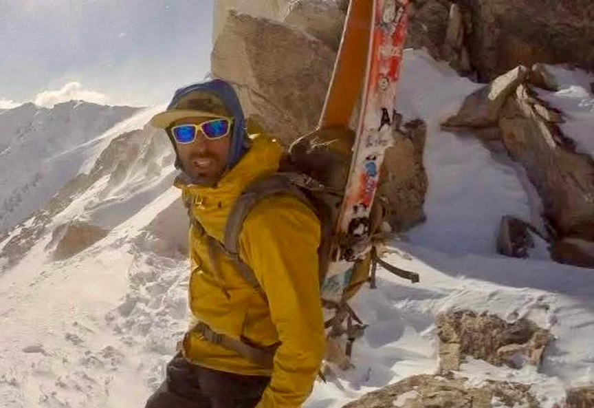 skier with skis on his back in mountains