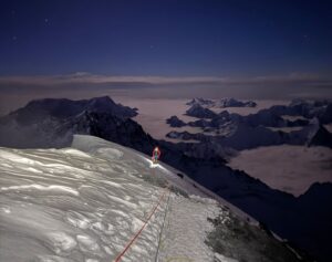A climber on Everest summit ridge under the stars