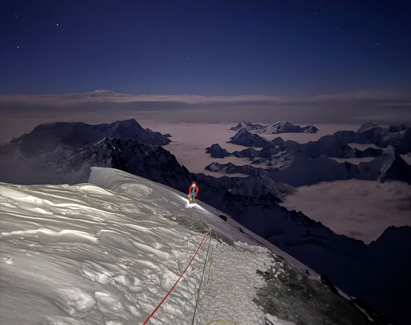 A climber on Everest summit ridge under the stars