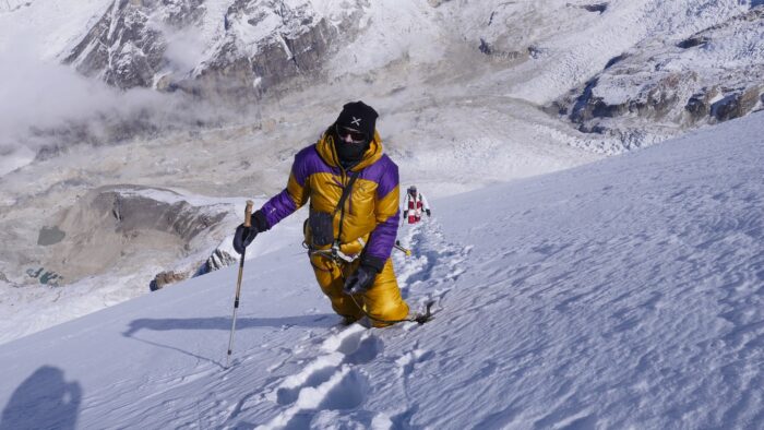 Nives Meroi in high-altitude dawnsuit, on a snow slope sinking up to the knees.