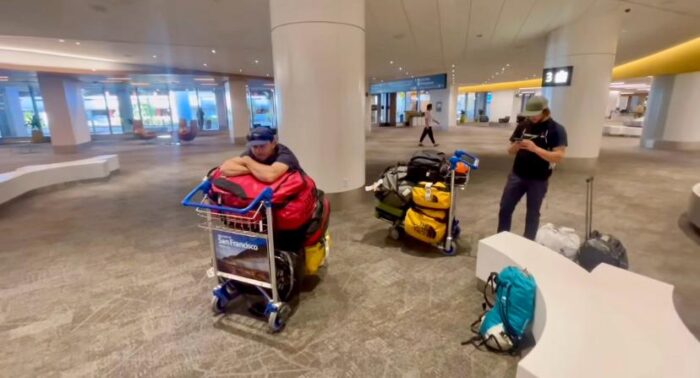 Climbers looking desperate at an airport lounge, leaning on their bags-filled trollys