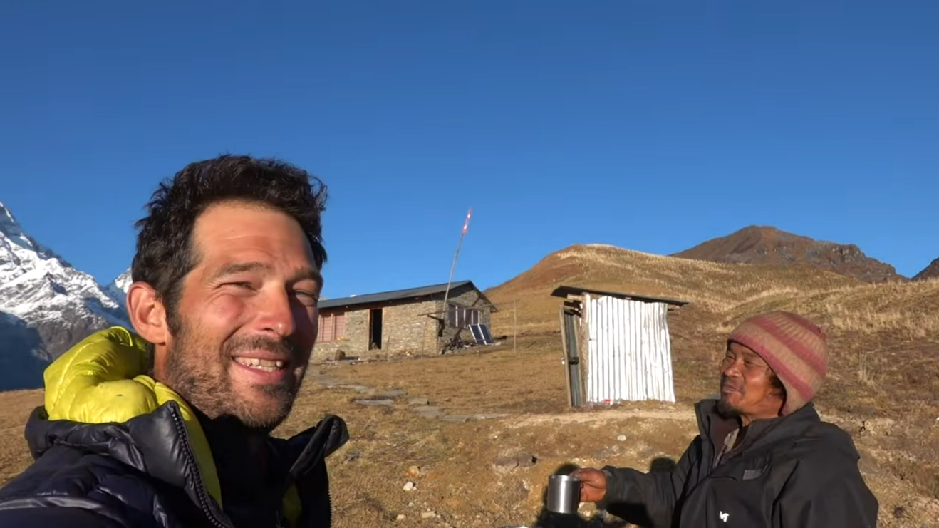 Two men smiling with a mountainside in the background