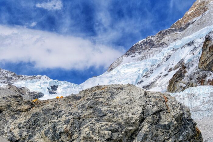 A rocky wall leading to some tents on top