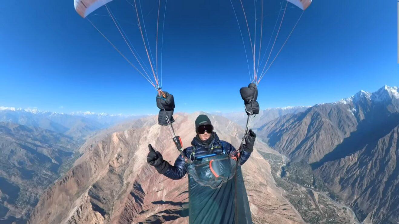 A man paragliding over a vast mountain range.