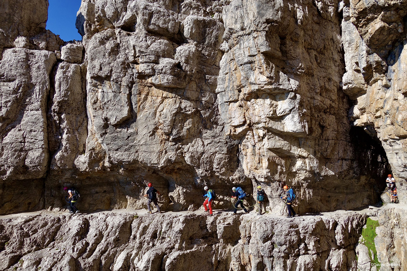 climbers edge along a ledge of a via ferrata