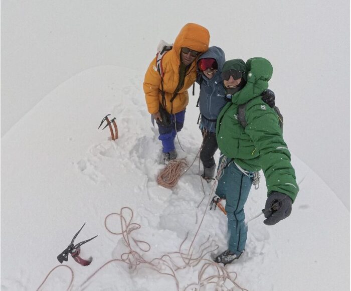 Climbers on a snowy summit in thick fog conditions.