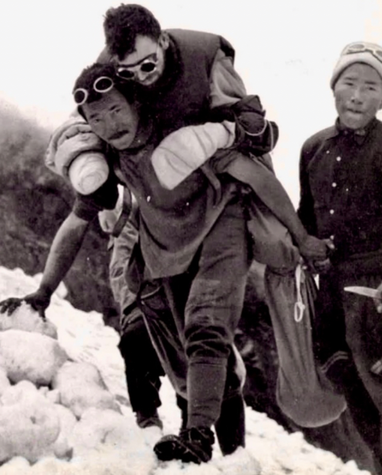A sherpa carries Maurice Herzog down Annapurna.
