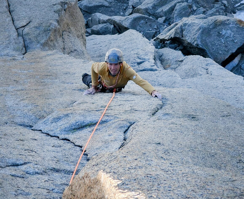 A climber on a vertical gratine face, climbing a system of cracks.