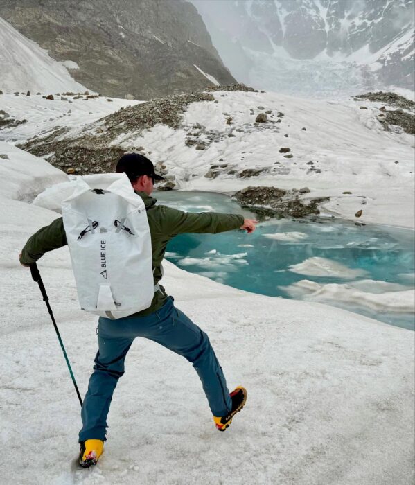 A climber in front of a pond blocking access in the middle of a glacier.