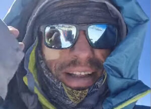 Close shot of Waldemar on a summit, with sunglasses and down hood.