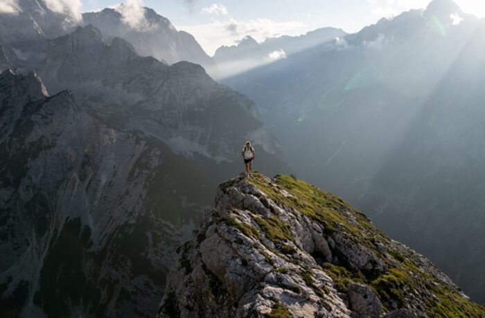 Laura Dahlmeier on top of a grassy mountain ridge as the light filters through the mist on the background mountains. 