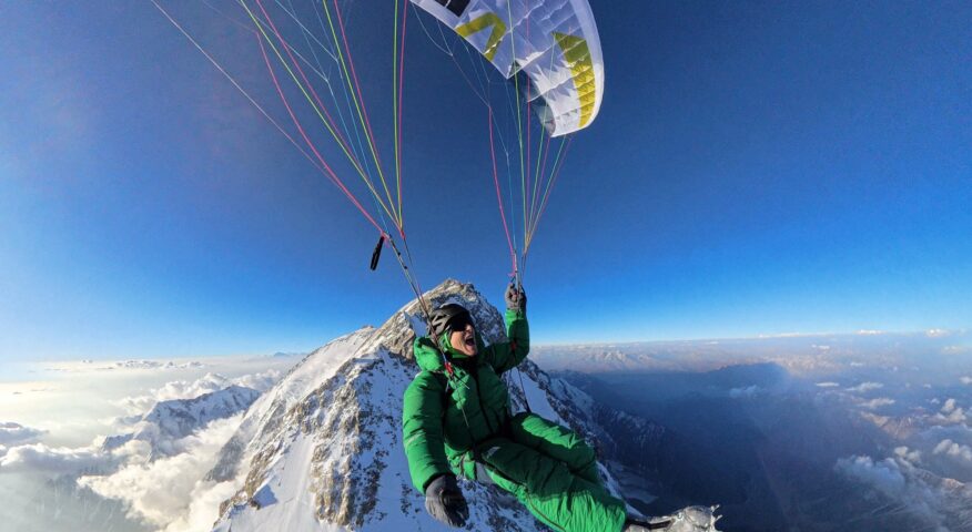 David Goettler takes a selfie as he paraglides from the top of Nanga Parbat at down, the mountain and the horizon at his feet.