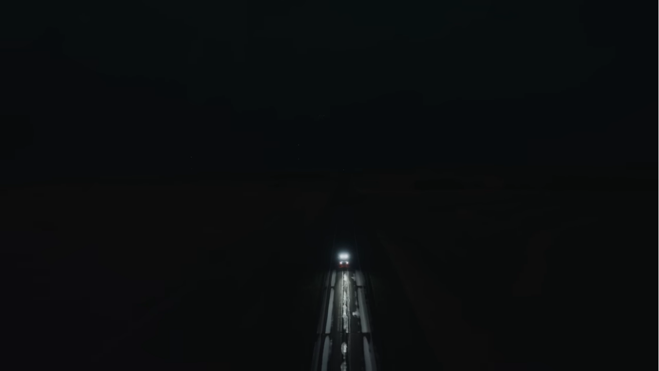 Headlights illuminate the road ahead in an otherwise black expanse