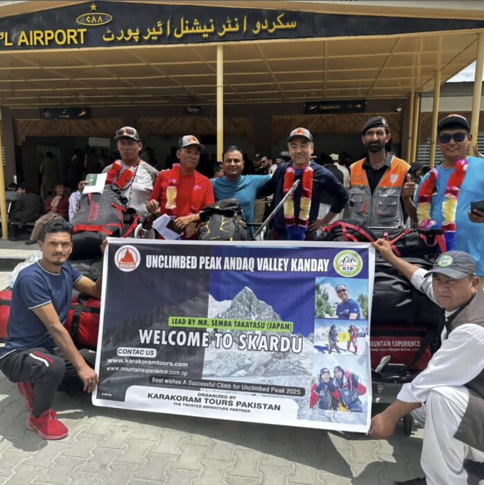 Cloimbers pose with an expedition banner in front of Skardu airport.