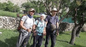 Three climbers pose in a garden with casual clothing.