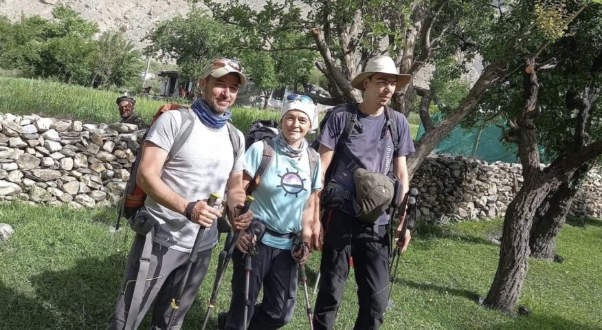 Three climbers pose in a garden with casual clothing.