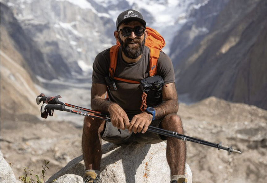 bearded hiker sitting with hiking poles