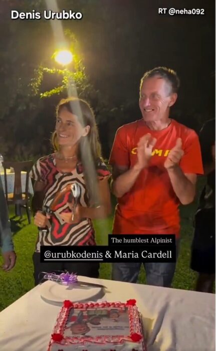 Cardell and Urubko applaud during an open-air evening celebration, with a summit cake in front of them.