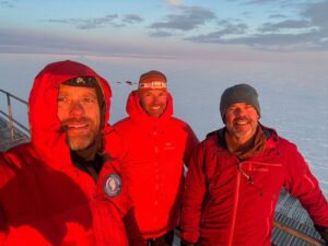 portrait of three polar travelers in orange parkas