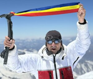 Colibasanu holds an ice-axe with a ribbon attached, colored like the Romanian flag.