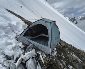 A tent on a slanted slope of snow and scree on K2
