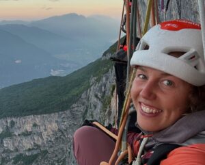 LAura Dahlmeier smiles from a ledge on a limestone wall in the Dolomites.