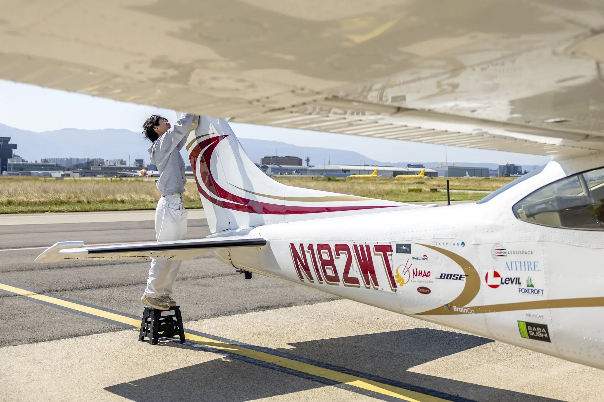 A young man, Ethan Guo, beside a small plane