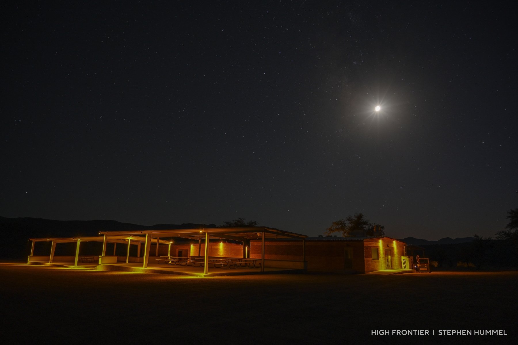A building with red lighting beneath the moon.