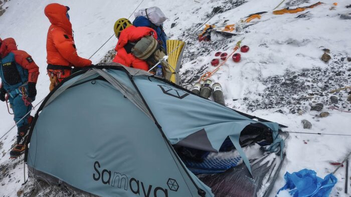 A ragged tent on a rock and snow slope. 