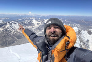 Sakhi points to mountains in background from a snowy summit.